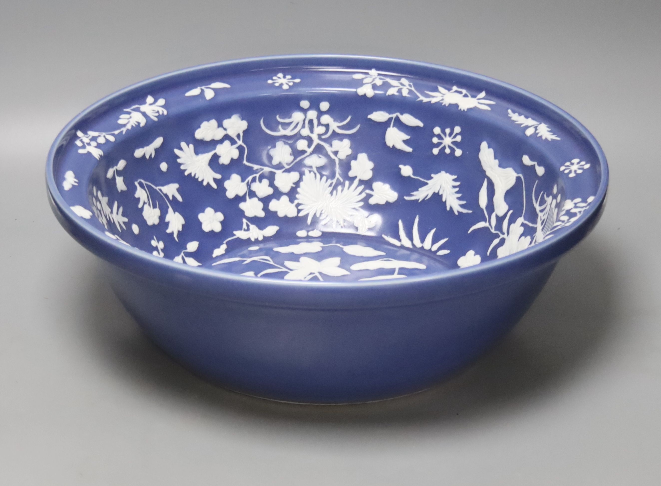 A large Chinese blue and white porcelain basin, lightly relief moulded with plants, 40cm
